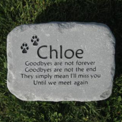 A personalized pet memorial stone engraved with the name 'Chloe', paw prints, and a remembrance quote, placed on green grass.
