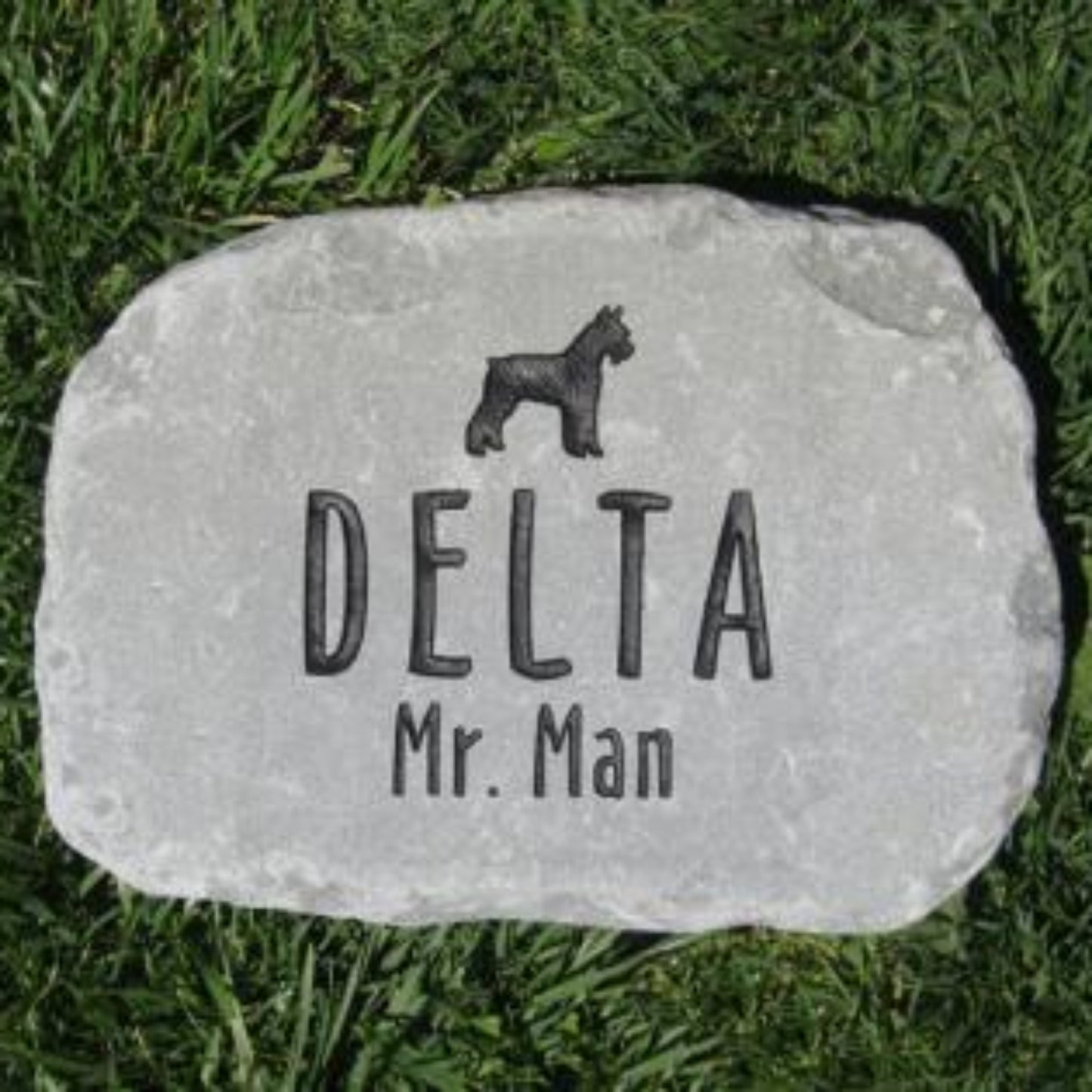 A personalized  stone dog memorial plaque engraved with a black dog silhouette, the name 'DELTA', and 'Mr. Man', placed on green grass.