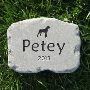 A personalized dog memorial garden stone with the name 'Petey', the year '2013', and a black silhouette of a dog, displayed on a green grass background.