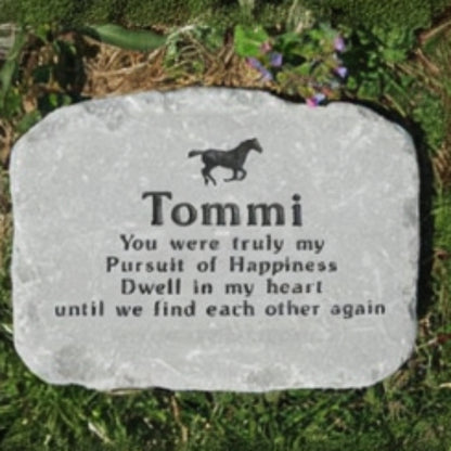 A personalized horse memorial stone engraved with a horse silhouette and the name 'Tommi' with a sentimental quote, placed on grass.