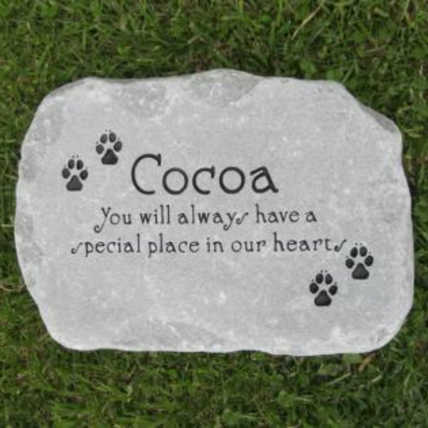 A personalized pet memorial garden stone with the name 'Cocoa' and the text 'You will always have a special place in our hearts' engraved, displayed on a green grass lawn.