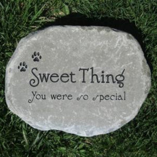 A personalized pet memorial garden stone engraved with 'Sweet Thing You were so special' and two paw prints, placed on green grass.